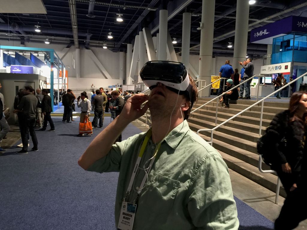A person wearing virtual reality goggles standing in a crowded exhibition hall at the Consumer Electronics Show.